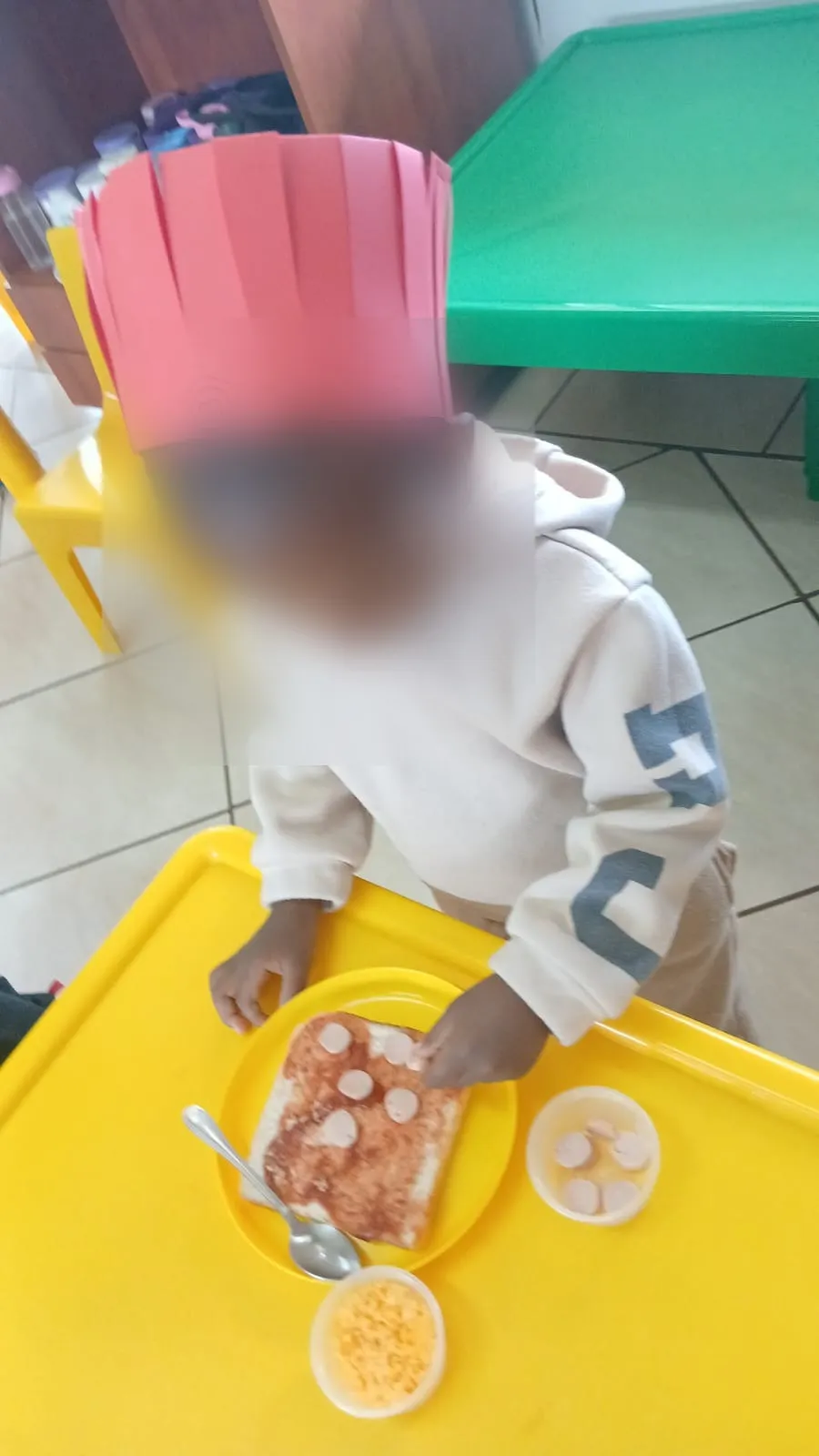 A little chef placing vienna slices on his pizza toast