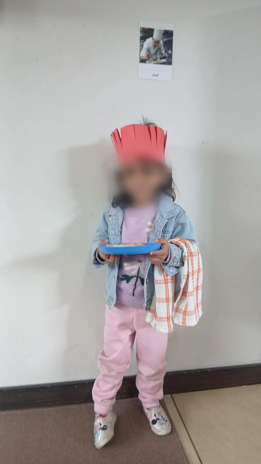A little chef in a denim jacket carrying her plate