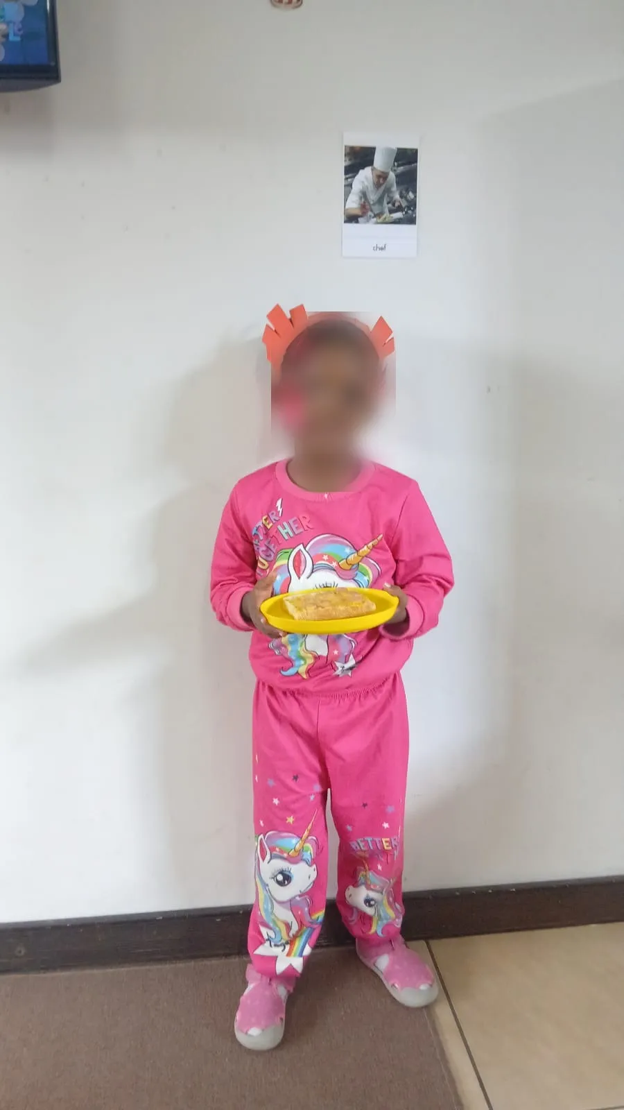 A little chef in pink holding up her finished pizza toast