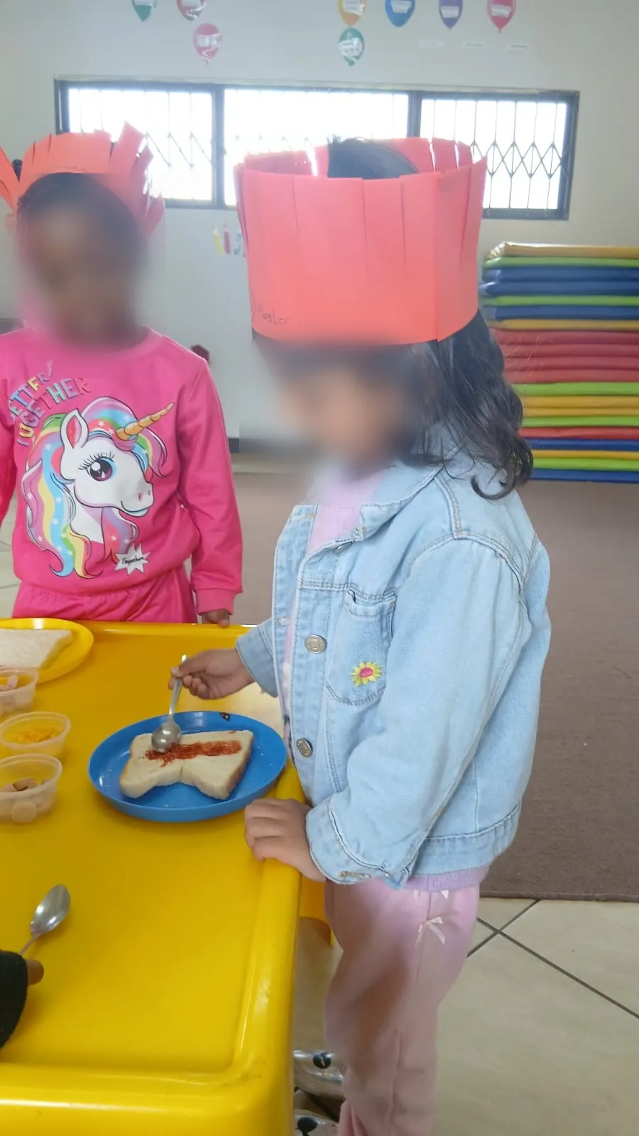 A little chef spooning tomato sauce onto her bread