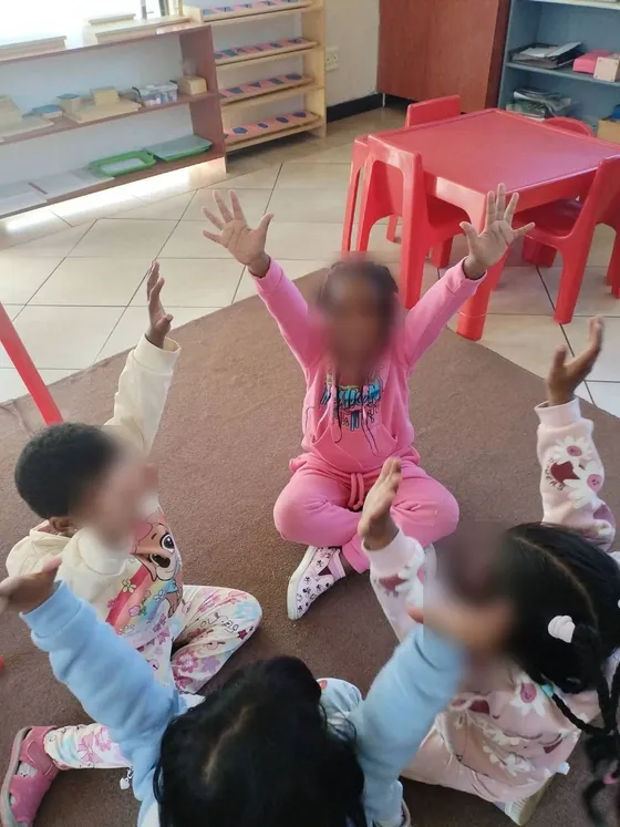 Children at circle time with their arms raised
