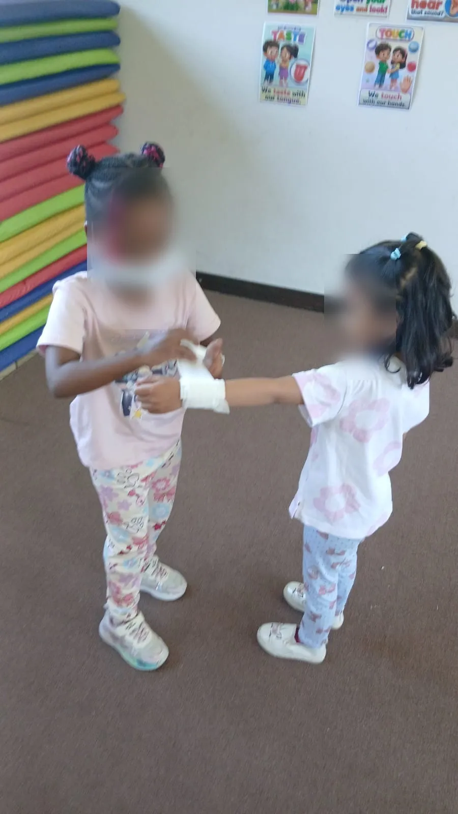 A child in a face mask bandaging a friend's arm
