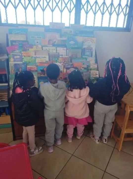 Four children choosing books from the reading corner