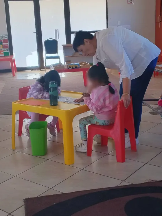 A guide with two girls at a bright yellow child-sized table