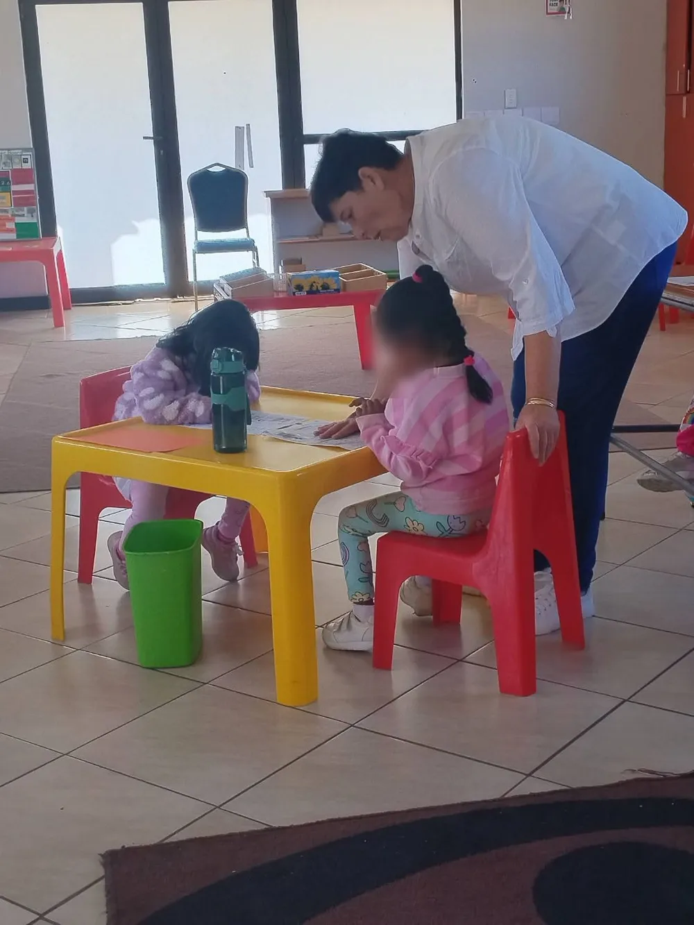 A Royal Kids guide helping two girls at a yellow child-sized table